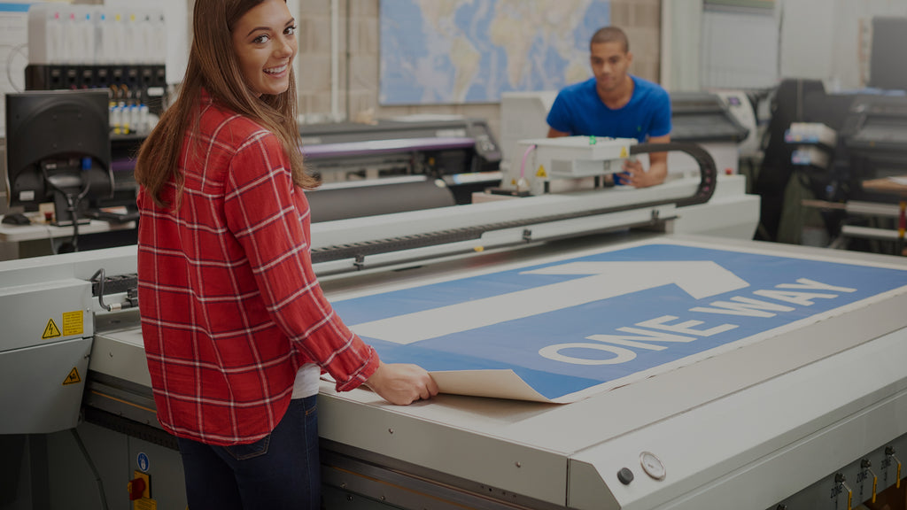 two people printing a road sign. Adhesive tape is used on the back